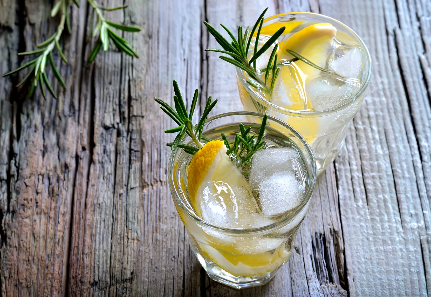 Lemon and rosemary soda with ice cubes in glasses or maybe refreshing summer alcoholic cocktail
