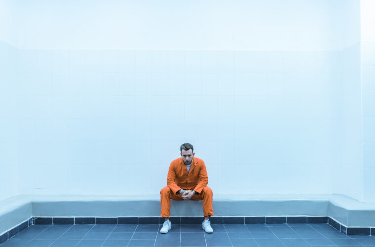 Prisoner sitting on bench in prison room
