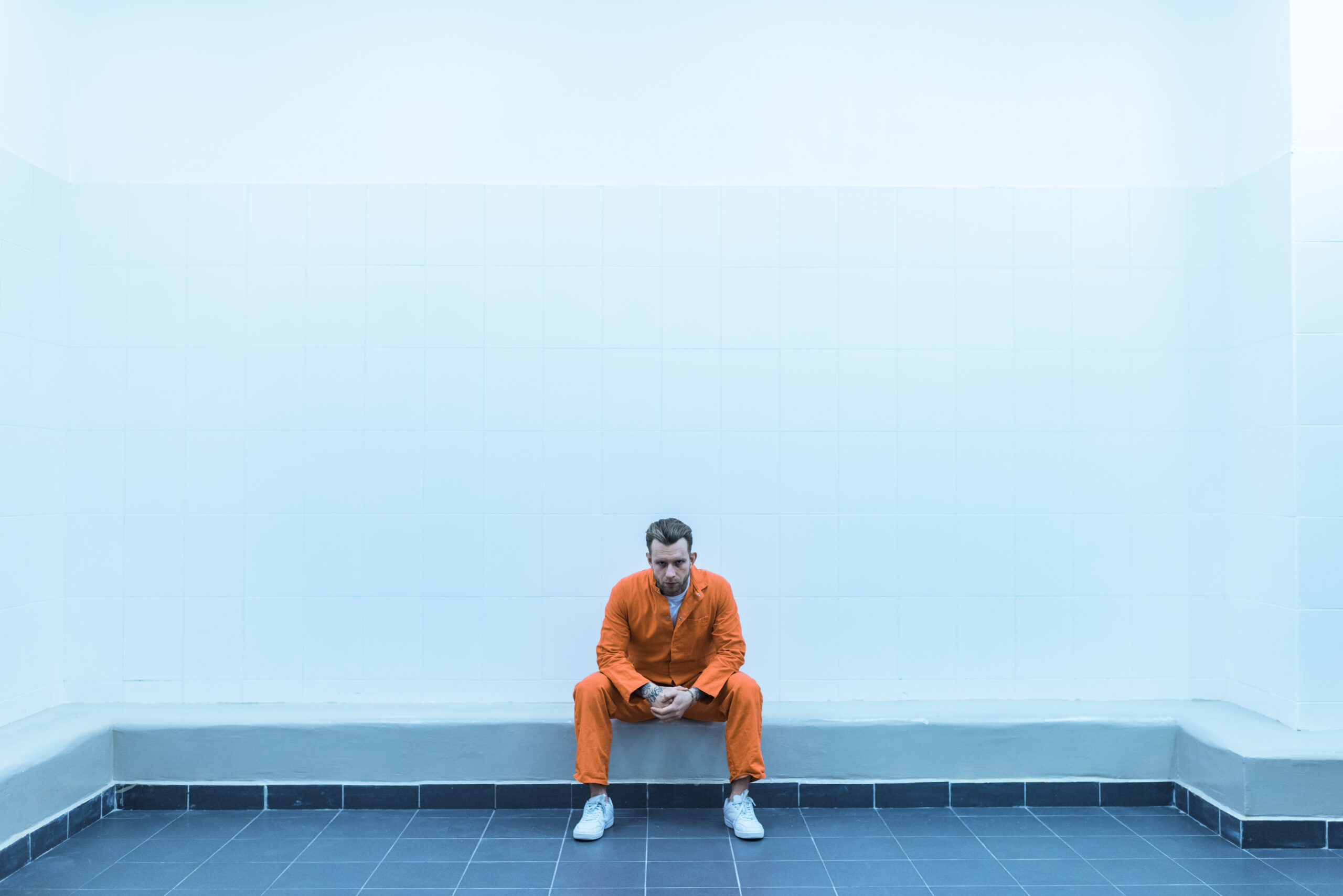 Prisoner sitting on bench in prison room