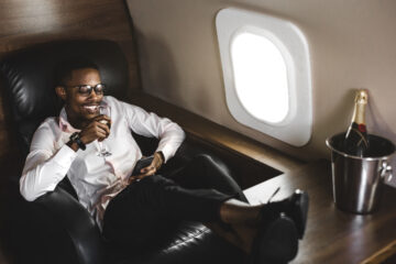 Black man on private jet drinking champagne