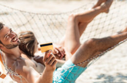 Young couple in hammock holding credit card