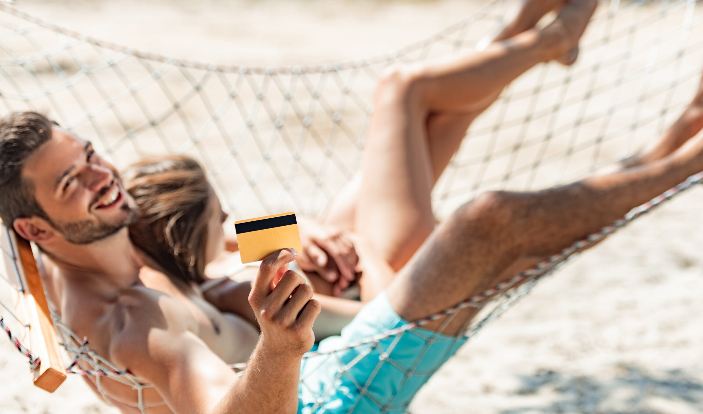 Young couple in hammock holding credit card
