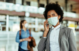 Passenger talking on smart phone while wearing face mask at the airport during virus epidemic.