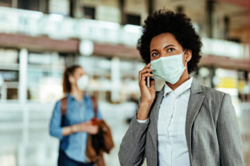 Passenger talking on smart phone while wearing face mask at the airport during virus epidemic.
