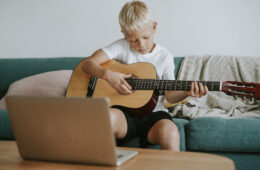Boy learning to play guitar through a video call