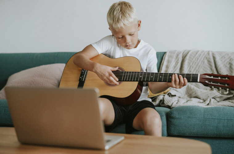 Boy learning to play guitar through a video call