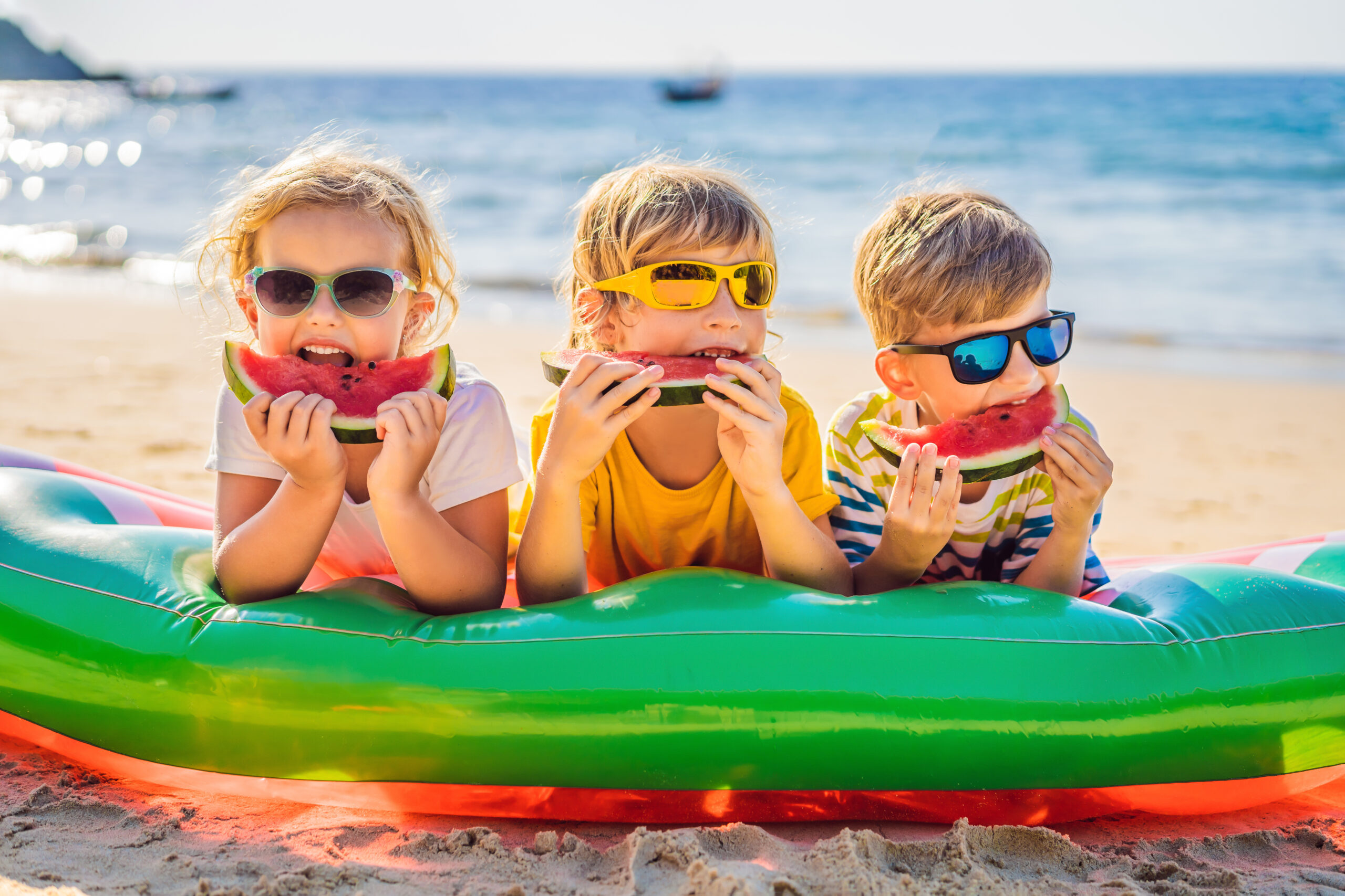 Children eating watermelon on beach