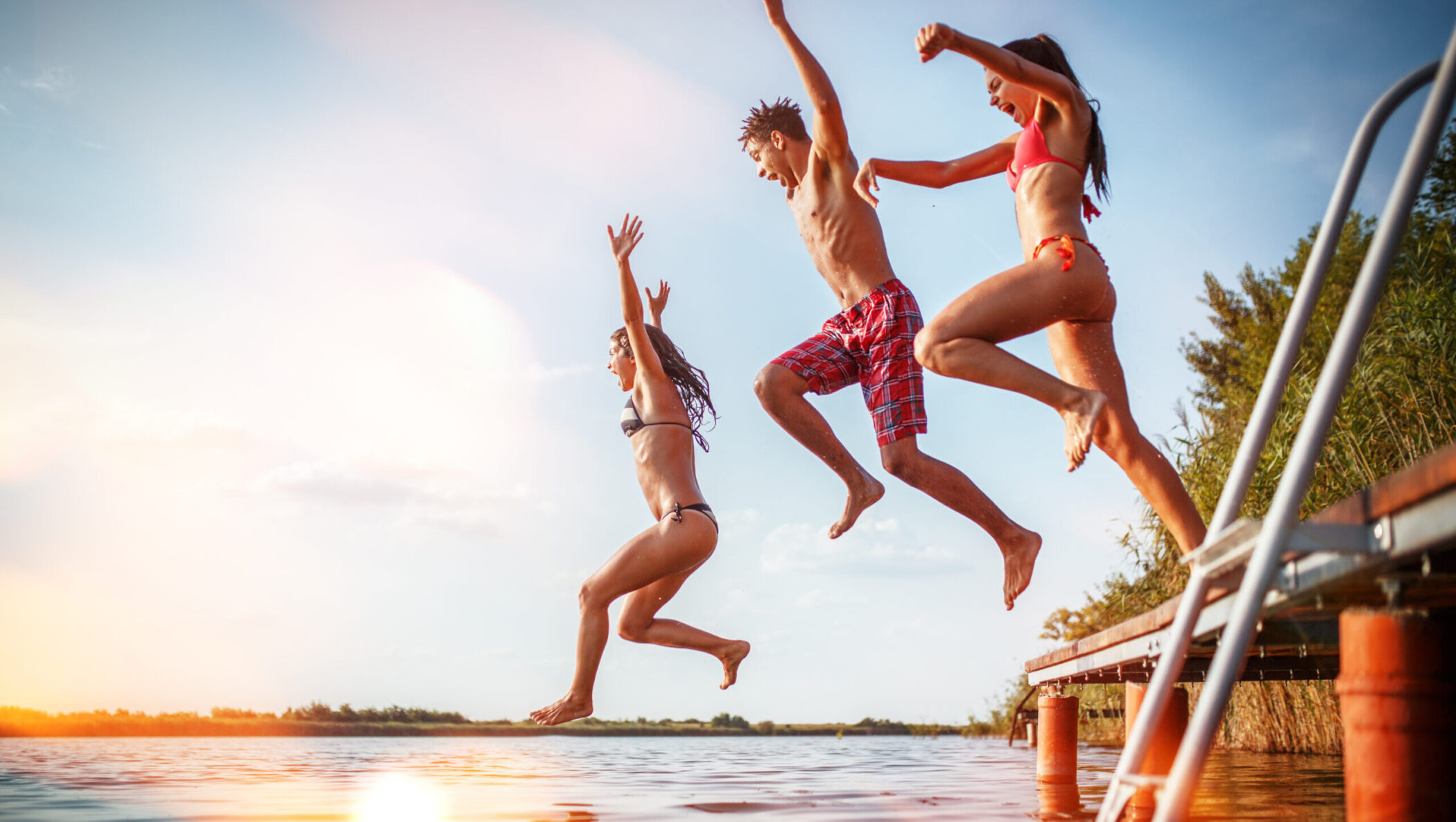 Group of friends jumping into lake