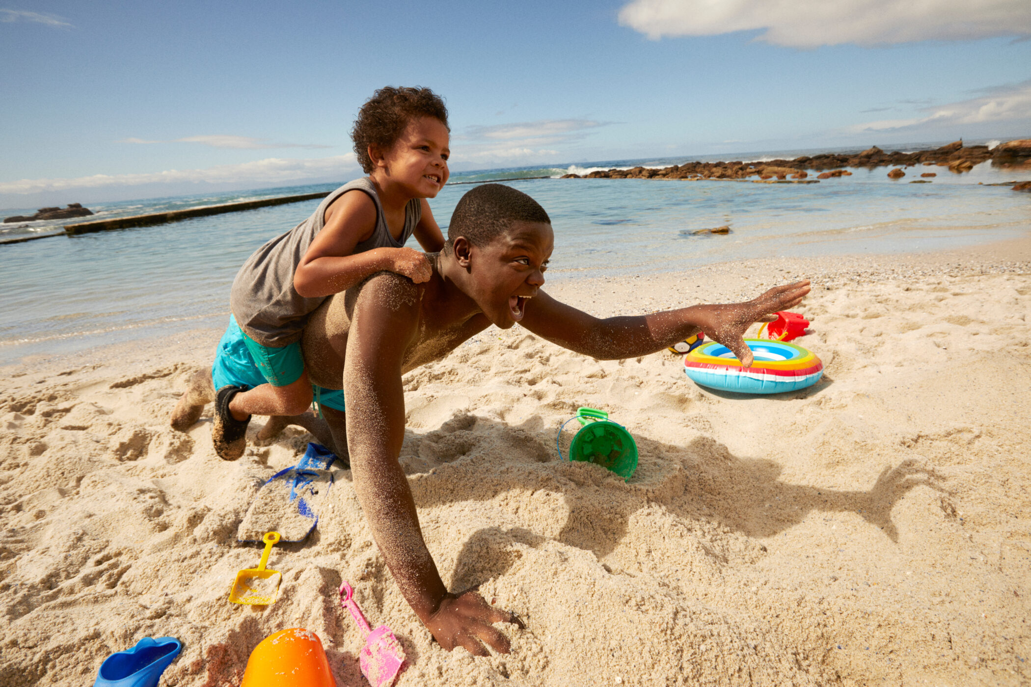 Young dad and son playing in sand during beach vacation