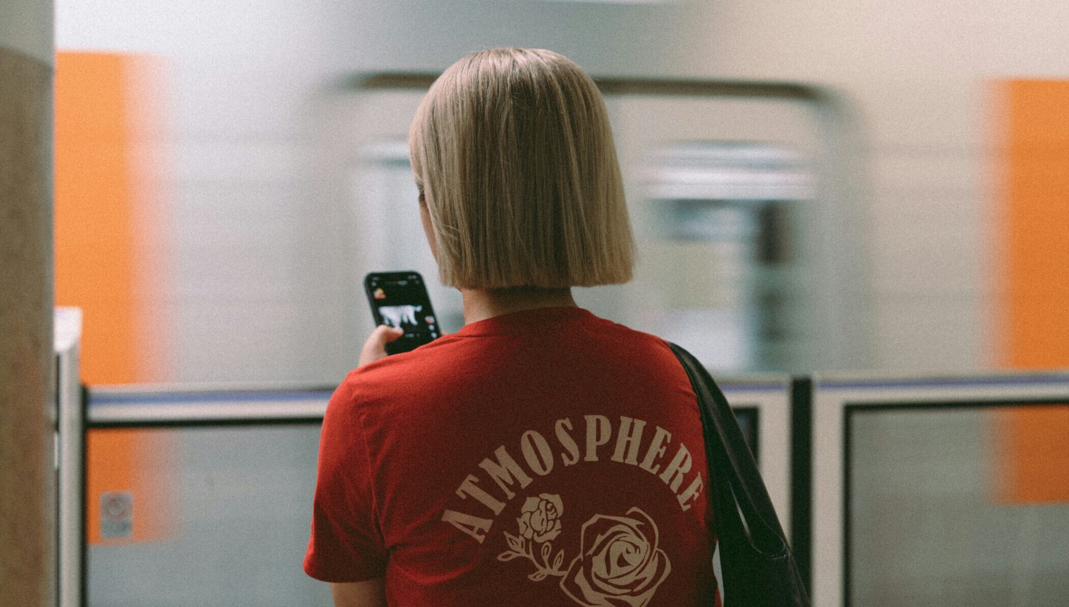 Woman standing by train with smartphone